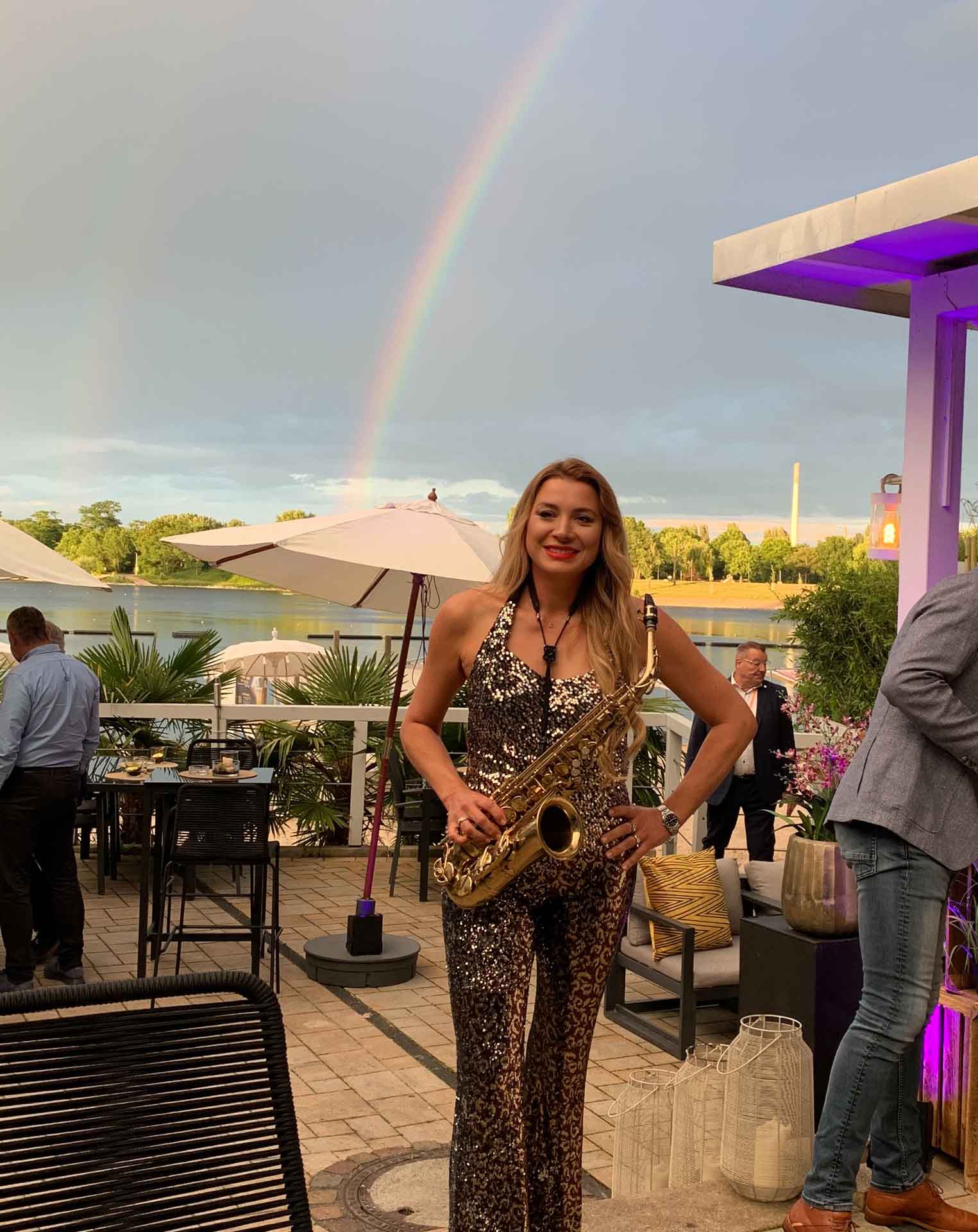 Saxophonist Natalie Marchenko at a DJ & Sax after-show party at the Seepavillon by Fühlinger See in Cologne with a rainbow over the lake