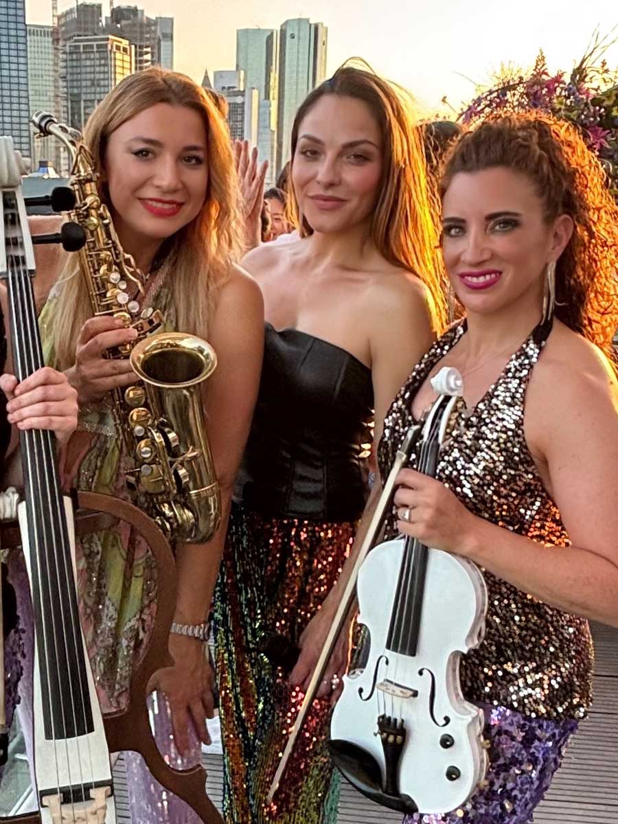 Damenband Frankfurt als mobiles Trio mit Saxophonistin und Geigerin im Sonnenuntergang über Mainhattan beim Merz Sommerfest