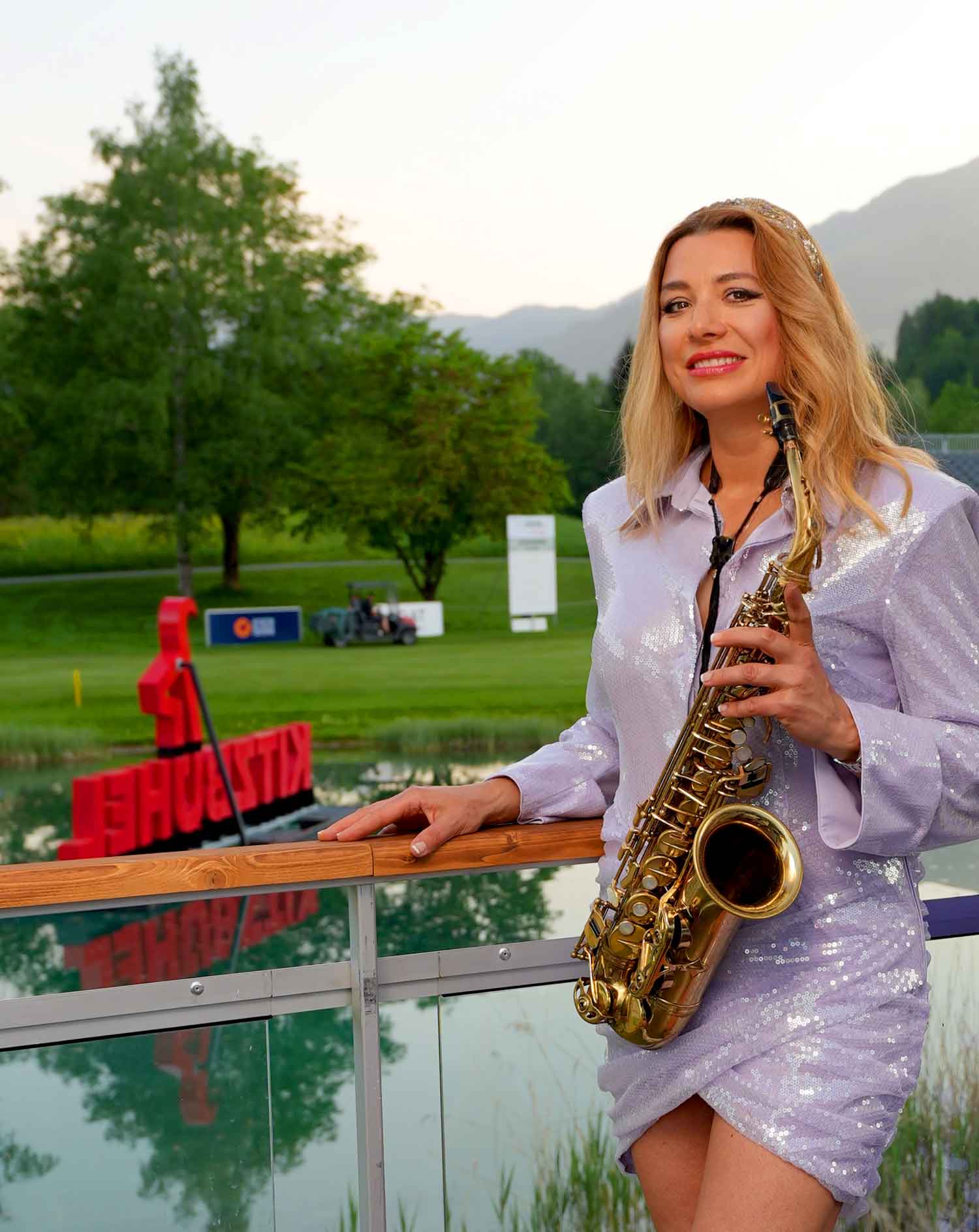Saxophonist Natalie Marchenko in front of the Kitzbühel scenery at the golf course in Tyrol